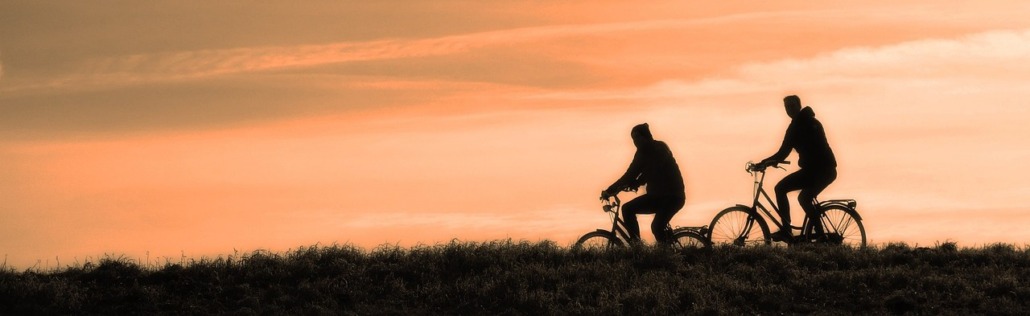 Deux personnes à vélo au coucher du soleil.
